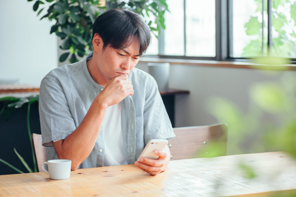 スマホを見て悩んでいる男性