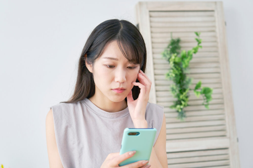 悩みながらスマホを見ている女性